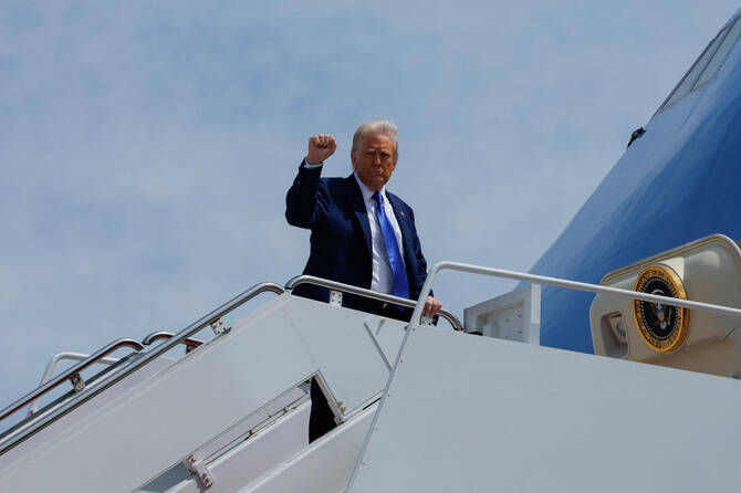 US President Donald Trump gestures, while he boards Air Force One, as he departs for Saudi Arabia, Qatar and the UAE.